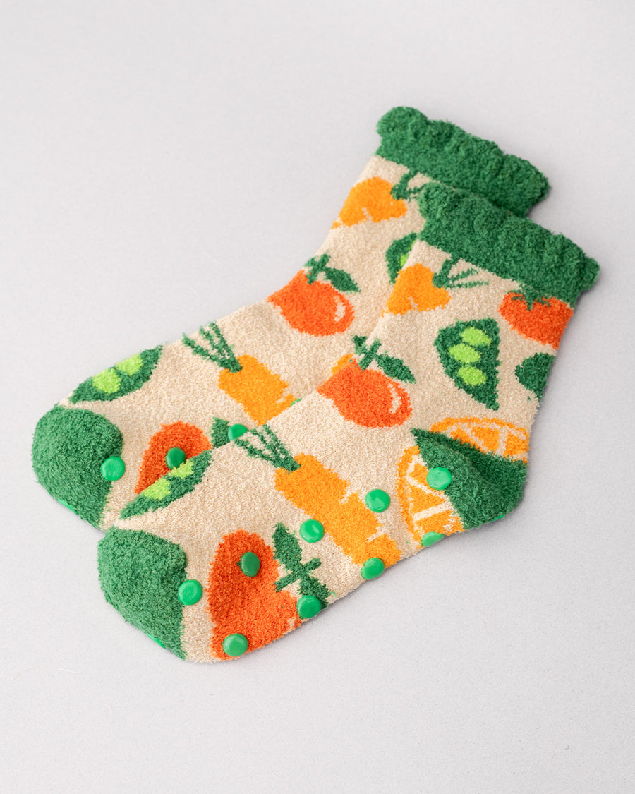side view of cream chenille socks with green ruffle top with all over veggie print and green grip bottom