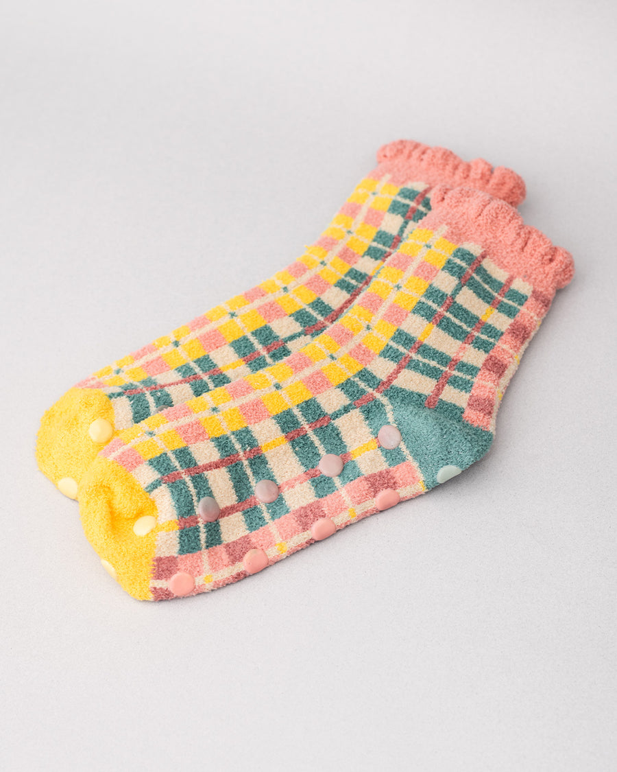 side view of coral, teal, cream and yellow plaid chenille socks with coral ruffle top and cream grip bottoms