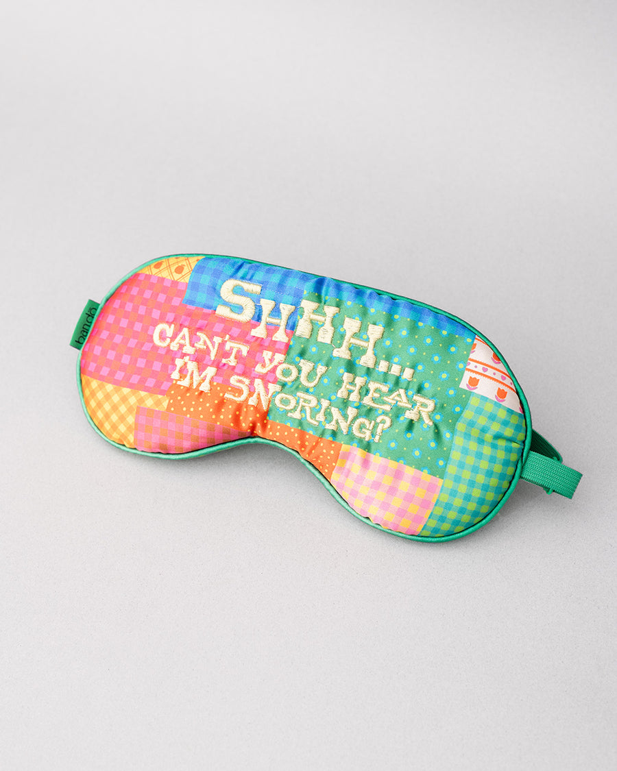 side view of colorful patchwork eye mask with cream 'shhhh...can't you hear i'm snoring?' across the front