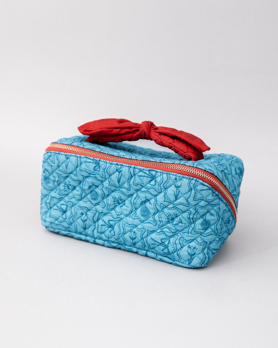 blue quilted zipper makeup bag with red bow handle and all blue floral and bow print