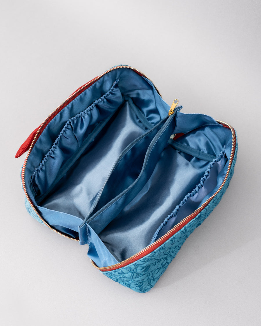 blue silky interior of blue quilted zipper makeup bag with red bow handle and all blue floral and bow print