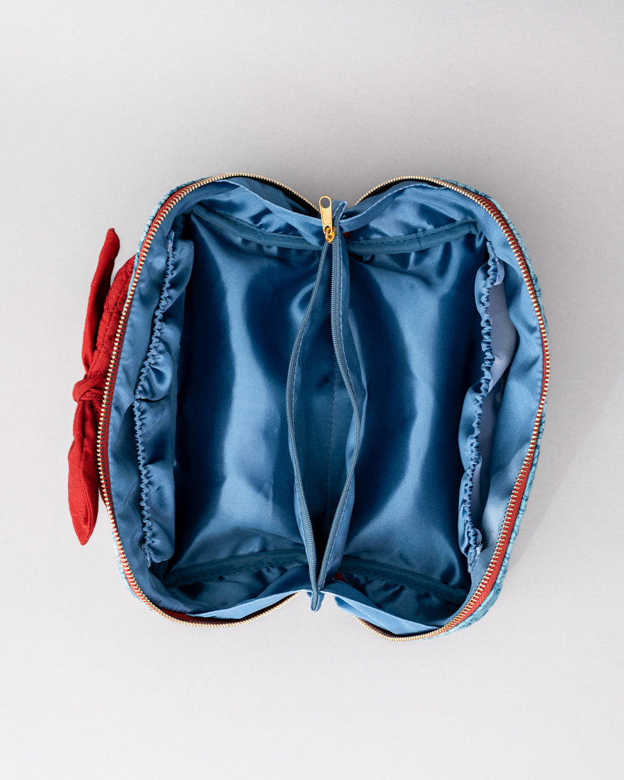 interior of blue quilted zipper makeup bag with red bow handle and all blue floral and bow print
