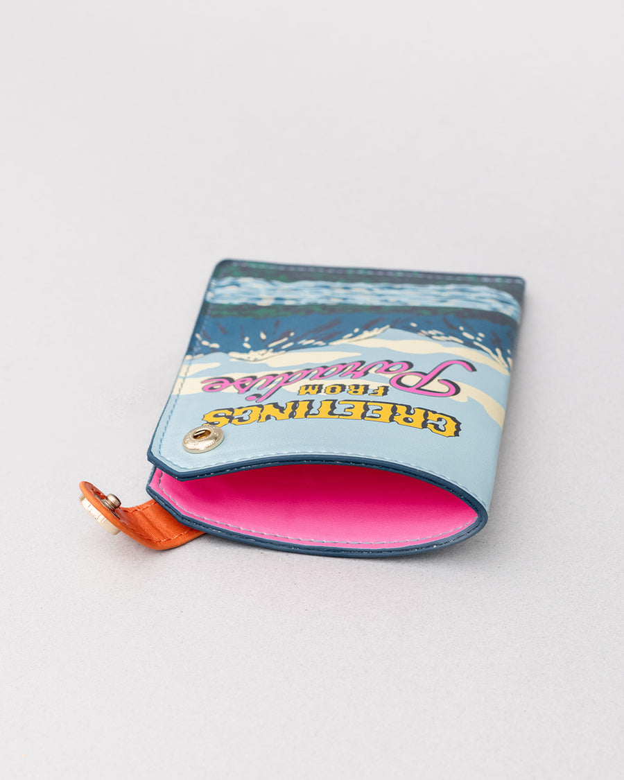 pink interior of passport holder with colorful mountain scene and 'greeting from paradise' across the front