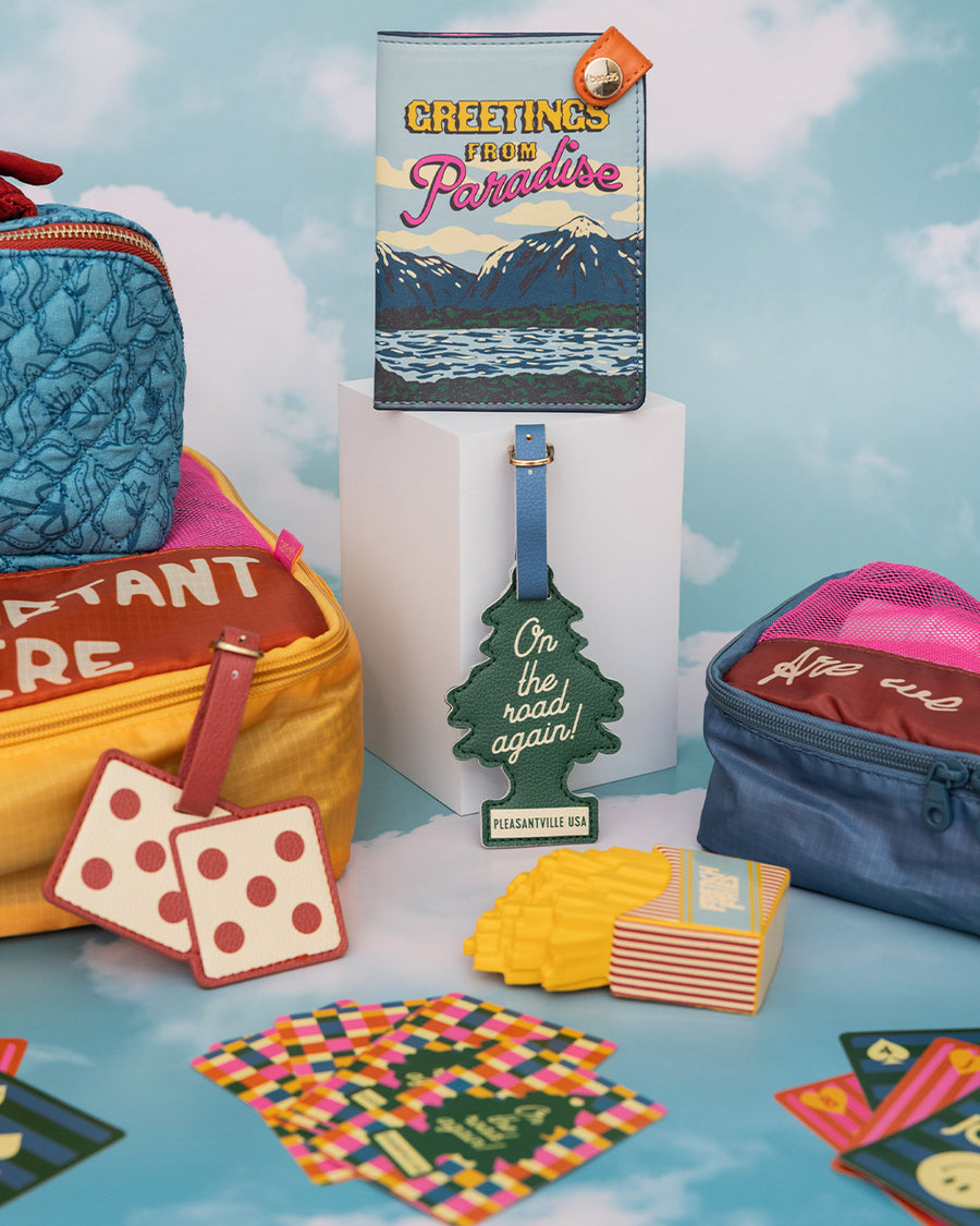 passport holder with colorful mountain scene and 'greeting from paradise' across the front surrounded by other items