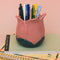 light pink tulip shaped pencil holder with pens inside on a stack of notebooks