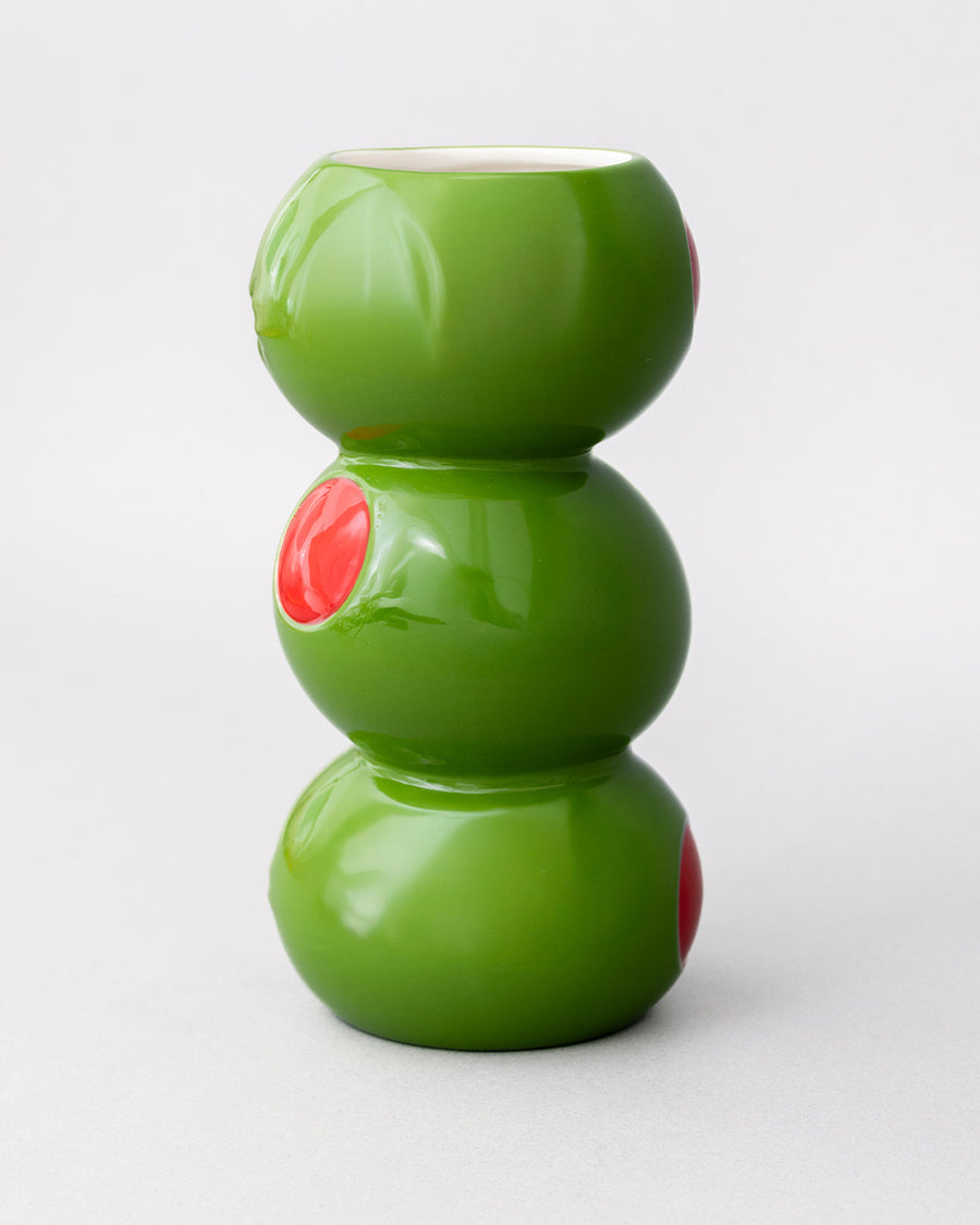 side view of three green olives stacked vase