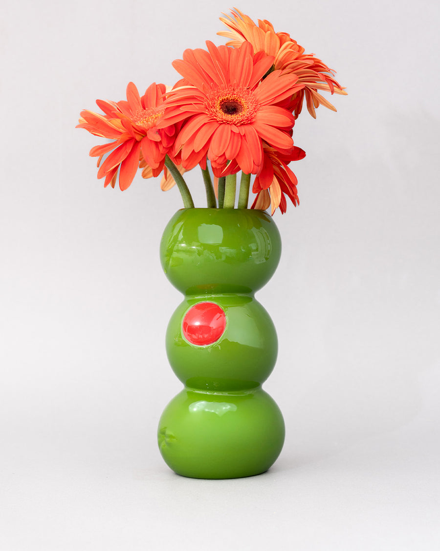 three green olives stacked vase with gerber daisies inside