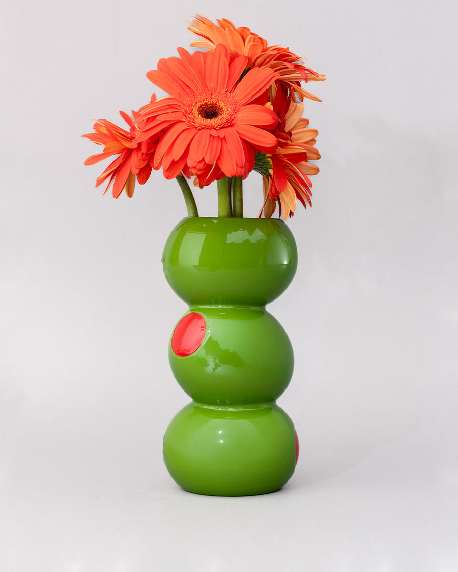 three green olives stacked vase with gerber daisies inside