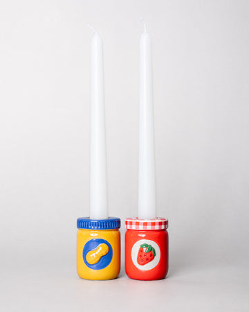 set of a peanut butter jar and jelly jar candle holders with white taper candles inside
