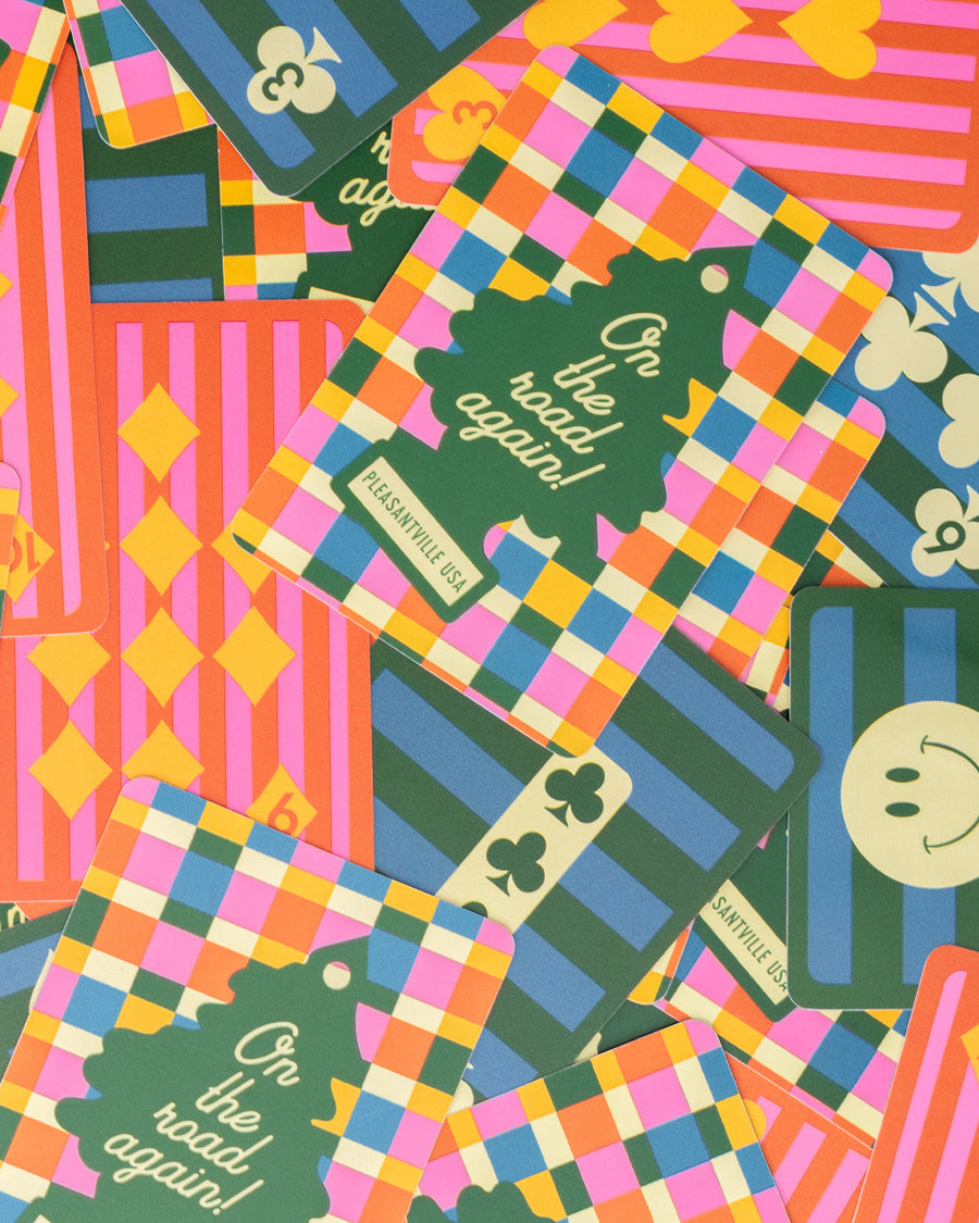 colorful waterproof playing cards with colorful checkered card case with green tree air fresher graphic that says 'on the road again! PLEASANTVILLE USA' on the back and colorful stripes on the face cards