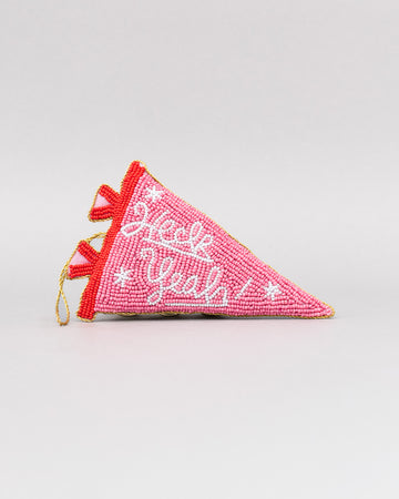 pink beaded pennant ornament with white cursive 'heck yeah!' across the front