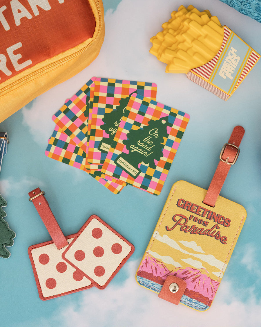 luggage tag with colorful mountain scene and red 'greetings from paradise' across the front on a blue background