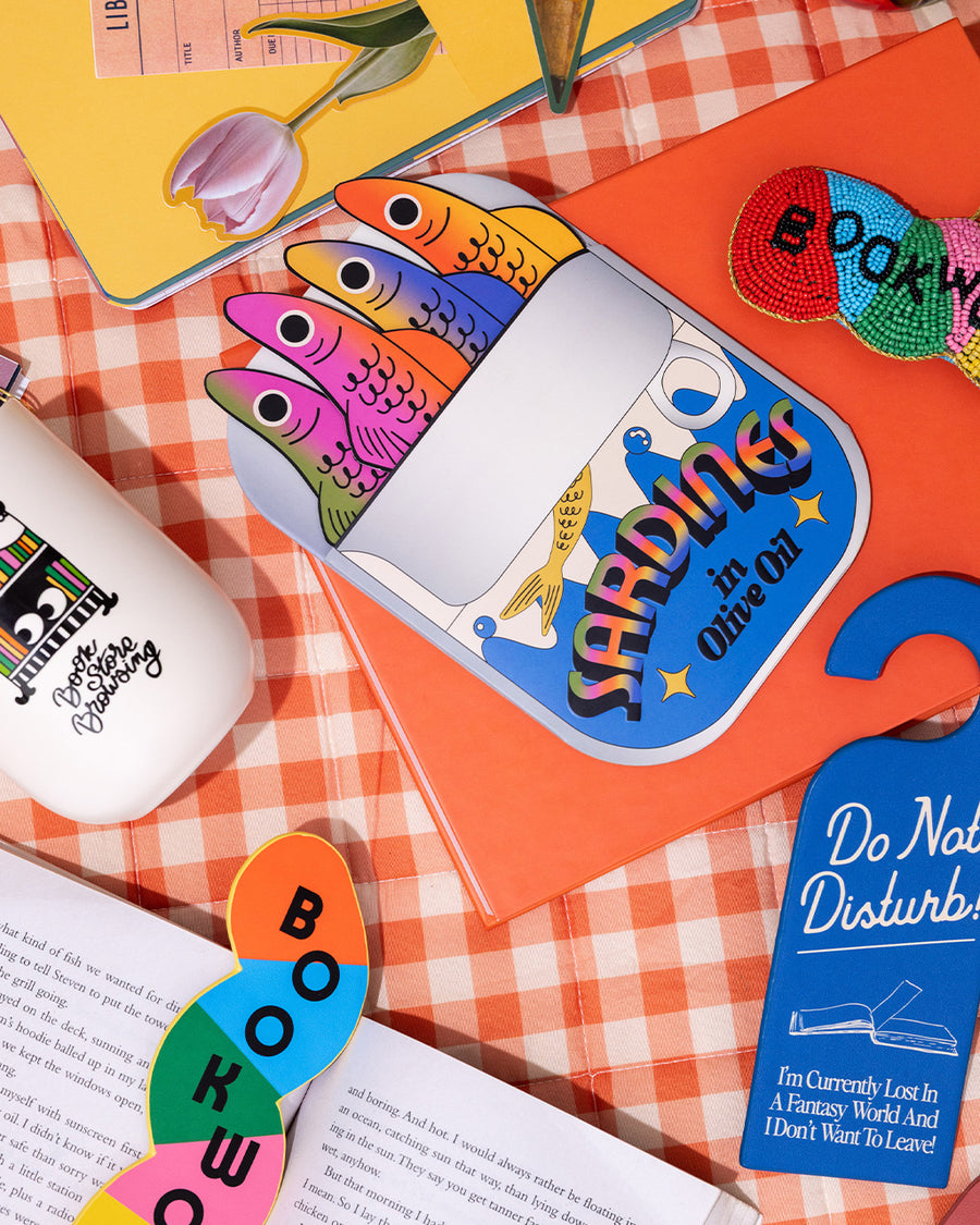 set of 4 colorful sardine bookmarks with 'sardines in olive oil can' holder on a gingham tablecloth surrounded by fun bookmarks