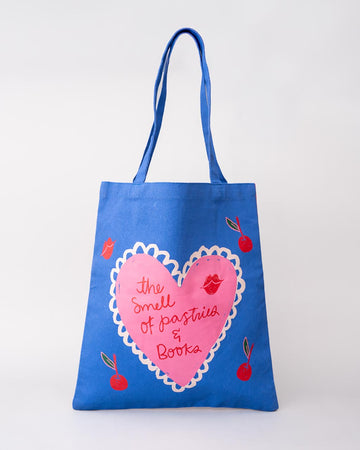 blue tote bag with pink heart and 'THE SMELL OF PASTRIES AND BOOKS' across the front