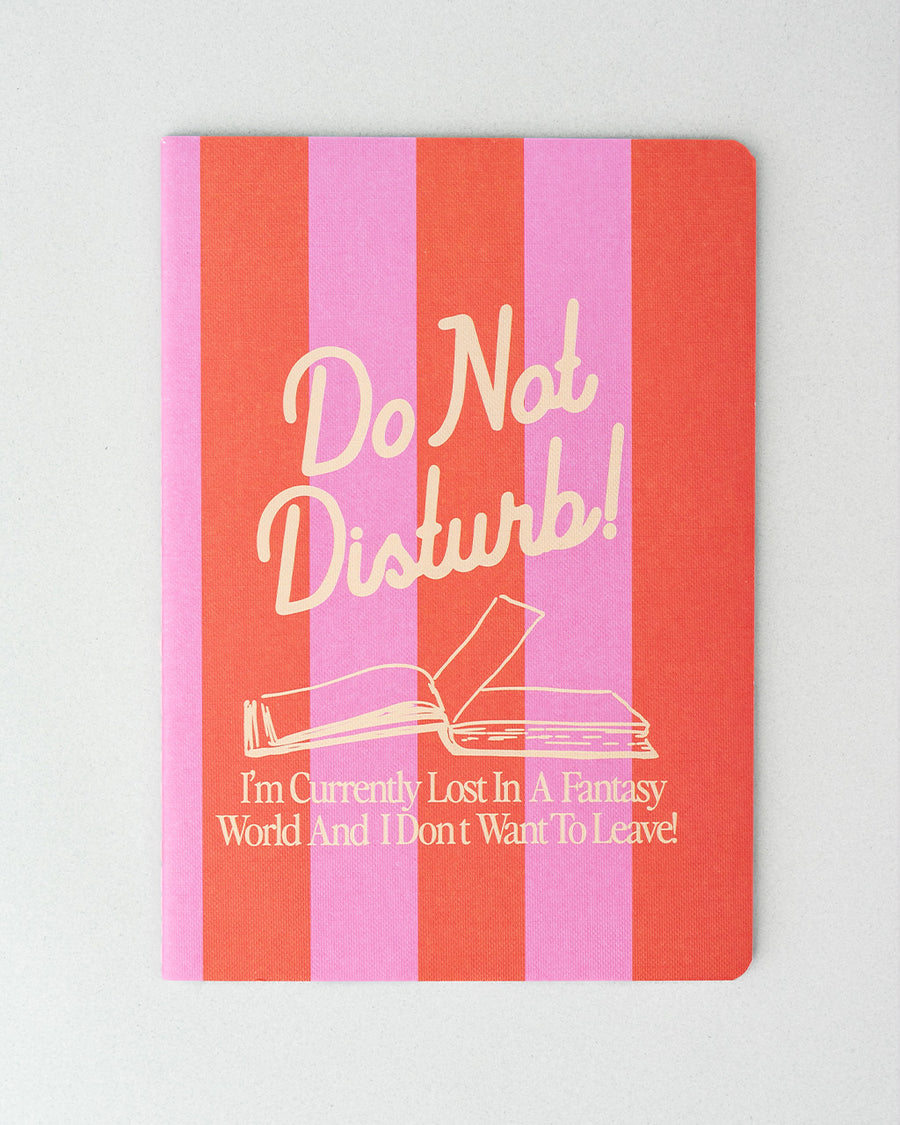 pink and orange striped notebook with 'do not disturb, i'm currently lost in a fantasy world and i don't want to leave!