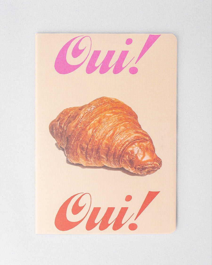 cream notebook with colorful 'oui! oui! and croissant