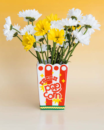 ceramic red stripe 'fresh popcorn' shaped vase with scalloped top with yellow flowers inside
