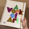 Gif showing the A Work of Art planner cover being rotated, so that the metallic letters shift colors.