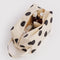 cream dopp kit with black polka dots with items inside
