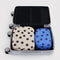 set of two packing cubes: blue polka dot and cream and black polka dot in a suitcase