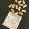 wooden domino set with white dots and dainty red flower print and comes in a red floral grid bag on a green background