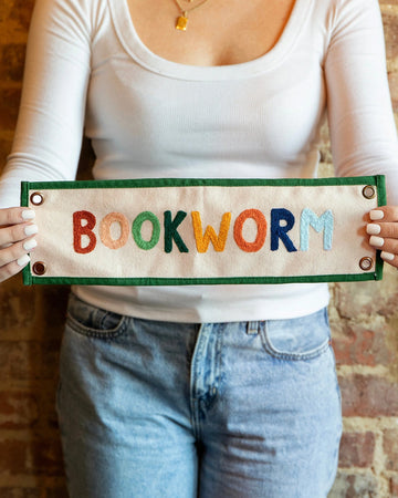 model holding canvas banner with rainbow 'bookworm' across the front and kelly green border