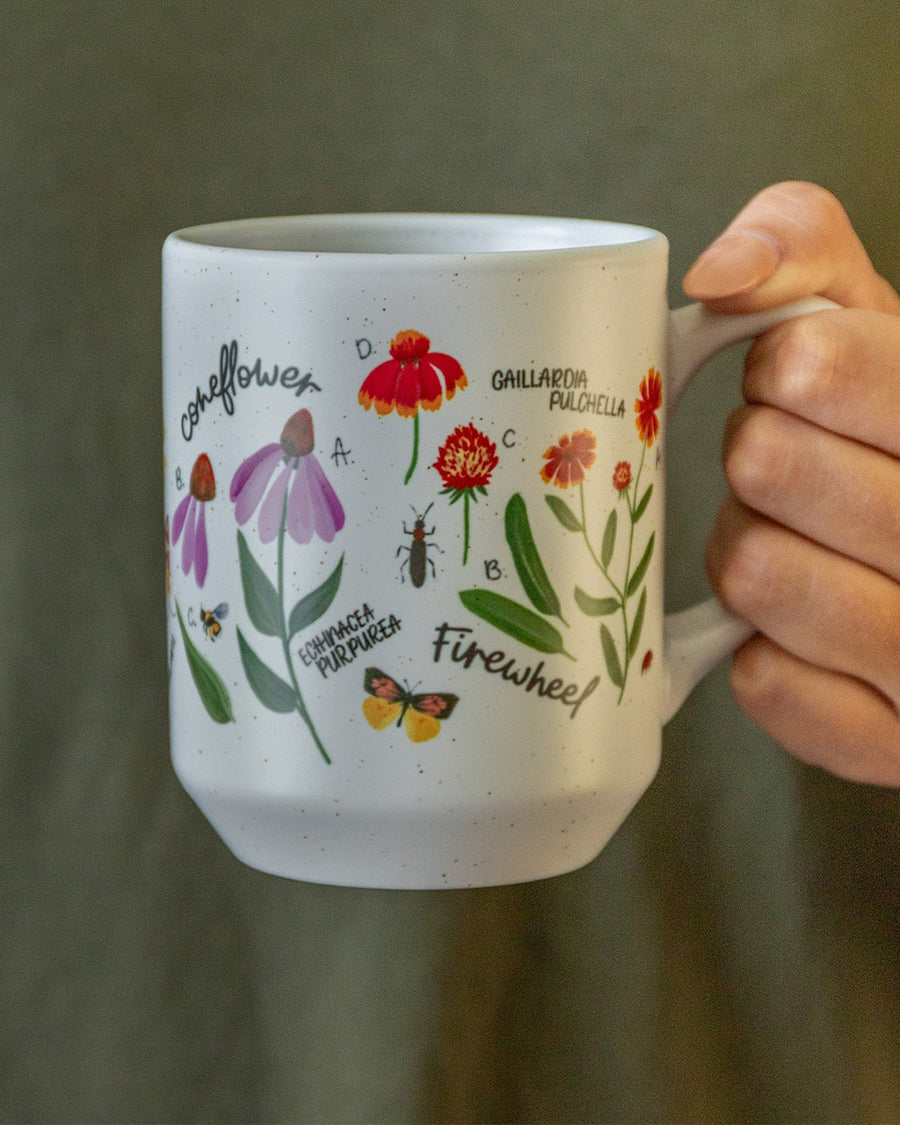 model holding white ceramic coffee mug with colorful wildflower botanical print