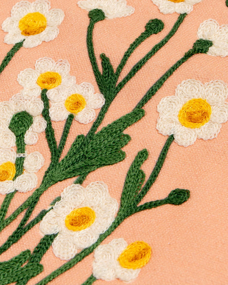 up close of white flowers of yellow, green and pink embroidered banner with wildflowers and 'wild at heart' across the top