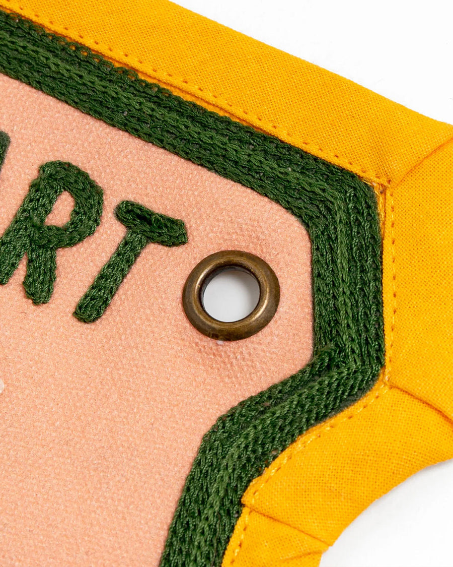 up close of grommet of yellow, green and pink embroidered banner with wildflowers and 'wild at heart' across the top