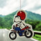 snoopy riding a blue and red motorcycle air freshener on a mountain background