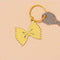 yellow enamel bowtie pasta keychain with key on it