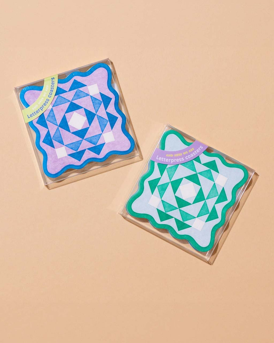 packaged set of 8 letterpress coasters with purple and blue scalloped kaleidoscope and green and light blue scalloped kaleidoscope