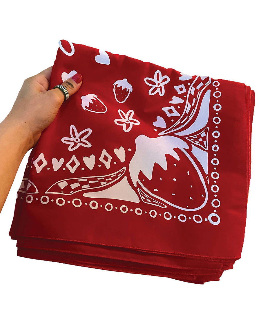 model holding folded red silk screened bandana with white strawberry design
