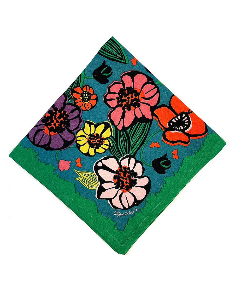 blue napkin with colorful abstract floral print with green trim along the edges
