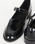 up close of black shiny leather loafer shoe with buckle and strap
