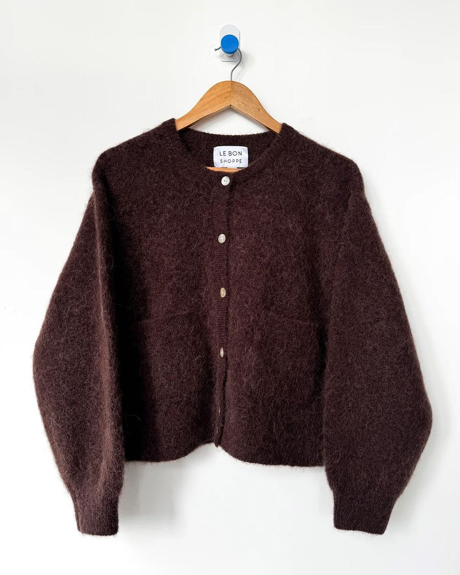 dark brown oversized cardigan with shell buttons and two front patch pockets on a hanger