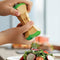 model using set of two wooden salt and pepper grinder in red and green