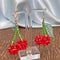 pair of beaded cherry dangle earrings hanging on a stand