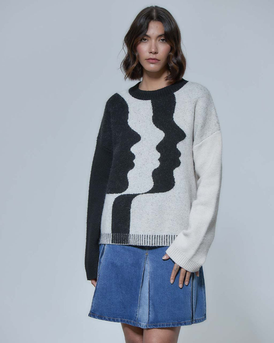 model wearing black long sleeve sweater with abstract black and white side view faces