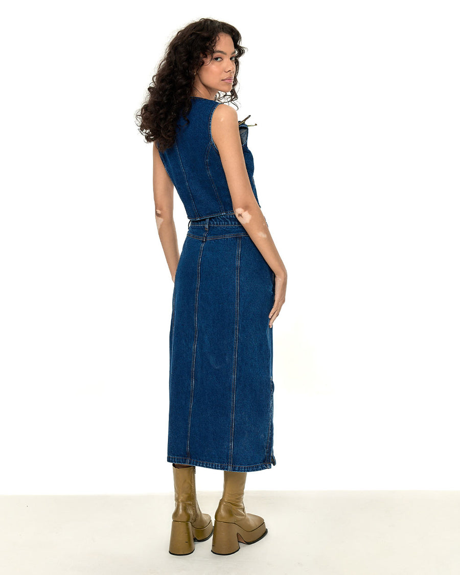 back view of model wearing denim maxi skirt with zipper slit and matching waistcoat