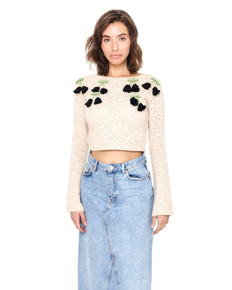 model wearing cream cropped sweater with 3D black rose details on shoulders
