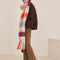side view of model wearing thick scarf with various shades of blue  and red checkers and fringe
