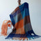 model holding up navy, light blue, orange and yellow checkered throw blanket with fringe