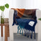 navy, light blue, orange and yellow checkered throw blanket with fringe on a white chair