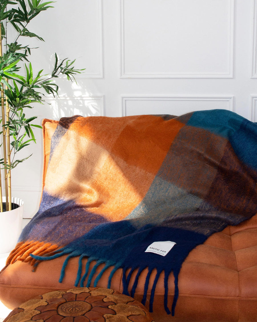 navy, light blue, orange and yellow checkered throw blanket with fringe on a couch