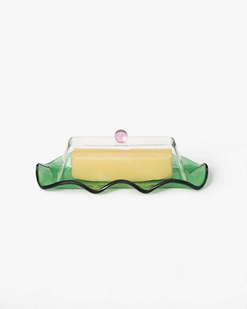 glass butter dish with clear lid and pink knob and green base with a stick of butter in it