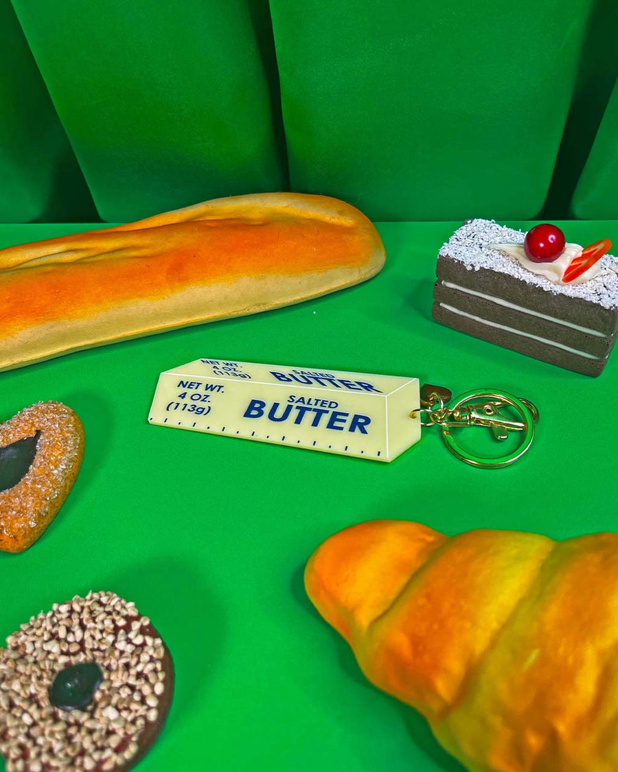 stick of salted butter keychain on a table with bread and pastries