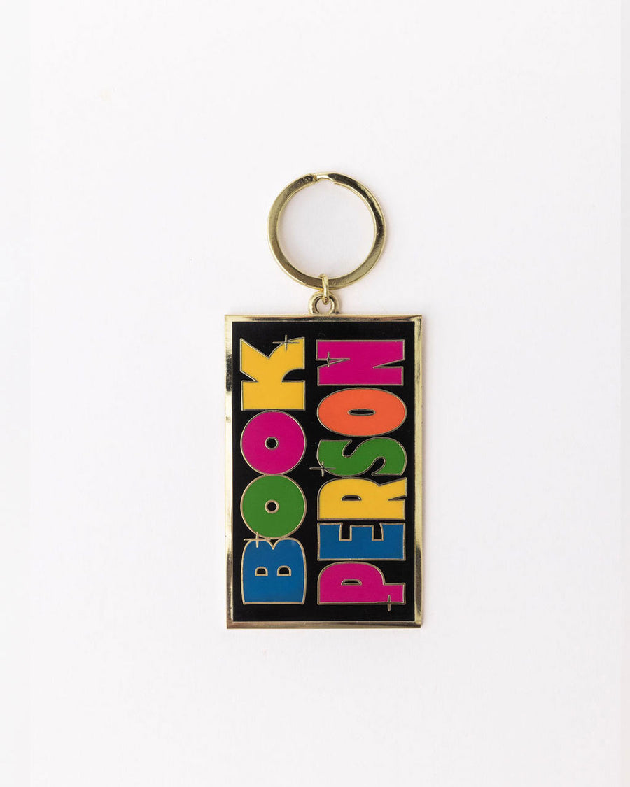 enamel keychain with black rectangle with colorful 'book person' across the front