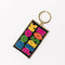 sideview of enamel keychain with black rectangle with colorful 'book person' across the front