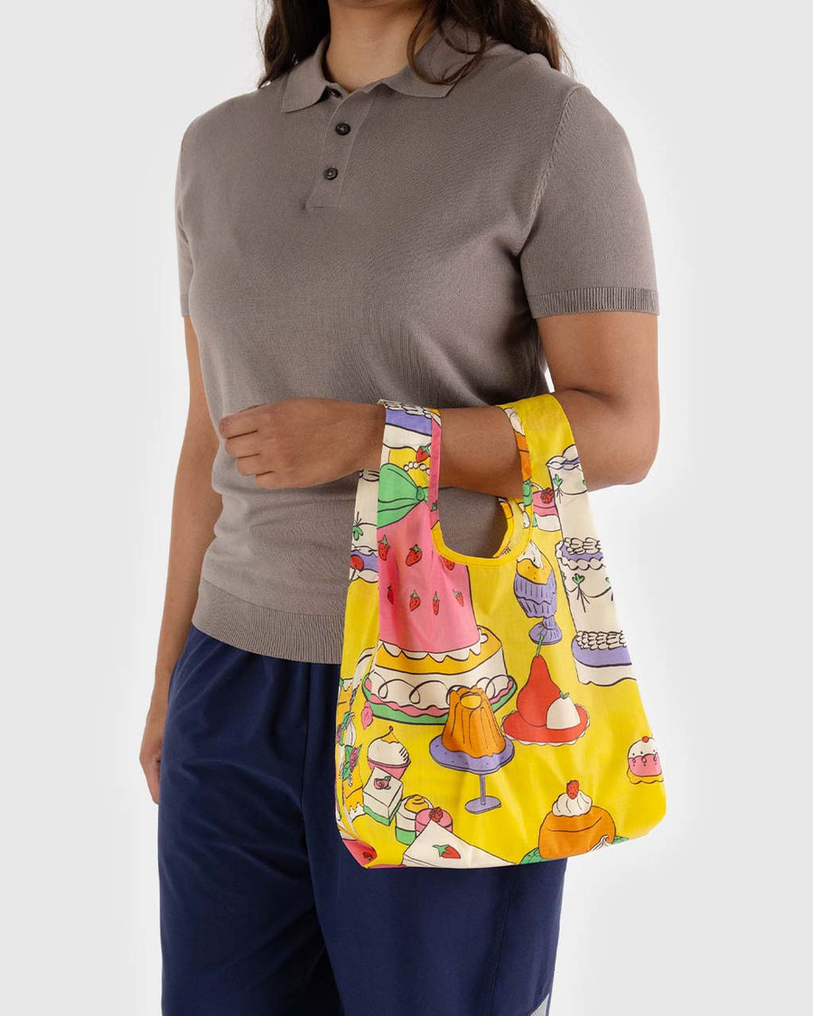 model holding yellow baby baggu with colorful abstract cake and pastry print